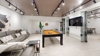 Located at 2475 Hurontario Street in Mississauga, this contemporary amenity space offers a well-appointed, single-floor layout designed for both socializing and relaxation. The interior is defined by a consistent modern aesthetic, featuring light wood-look tile flooring throughout, crisp white walls, and dramatic dark ceilings outfitted with adjustable track lighting that creates a polished, gallery-like atmosphere.

The kitchen is a standout feature, anchored by a generous island topped with a thick white countertop and finished with a dark wood-textured base. A row of upholstered velvet bar stools lines the island, making it an ideal gathering spot. Sleek, high-gloss white cabinetry lines the back wall, complemented by elegant black pendant lights that hang above the island, adding contrast and visual interest.

Adjacent to the kitchen, a comfortable lounge area is furnished with a leather sofa, accent chairs, and a glass coffee table, alongside curated wall art that adds warmth and personality to the space. A glass-paneled sliding door provides a seamless visual connection to the entertainment area, which centers around a full-sized pool table and a wall-mounted flat-screen television. Together, these zones create a versatile, amenity-rich space suited for a variety of social gatherings and recreational activities.