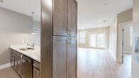 This well-designed single-floor residence offers a clean, contemporary aesthetic throughout, with light-toned luxury vinyl plank flooring and neutral warm-gray walls creating a cohesive, inviting atmosphere across every room. The open-concept living area is bright and airy, benefiting from natural light that streams in through windows fitted with blinds and a set of French doors that provide an additional access point. The kitchen is thoughtfully outfitted with dark-toned cabinetry, light quartz countertops, stainless steel appliances including a full-size refrigerator, built-in microwave, and dishwasher, along with a peninsula that separates the kitchen from the living space. Tall pantry-style cabinetry provides generous storage. The bedrooms are comfortably scaled, each featuring light-filled windows and well-proportioned closets with louvered bi-fold doors. The bathrooms are finished with large-format tile flooring, dark wood vanity cabinetry, white countertops, and full tub-shower combinations. Recessed lighting throughout the unit, along with pendant lighting accents in the kitchen, contributes to a polished and functional interior. Ample built-in storage and a practical layout make this a versatile and move-in-ready space.