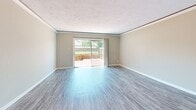 Located at 1191 Carlton Arms Circle in Bradenton, Florida, this two-story home offers a practical and comfortable layout spread across two floors. The main level features a spacious living room with wood-look laminate flooring, crown molding, and a textured ceiling. Sliding glass doors flood the space with natural light and open to an outdoor deck area, providing a seamless connection to the exterior. A pass-through window links the living area to the kitchen, which is equipped with white cabinetry, light countertops, and a double stainless steel sink positioned beneath a window that brings in additional natural light. Upstairs, two carpeted bedrooms offer a quiet retreat. The generously sized primary bedroom features soft carpet, neutral tones, and a window with natural light. The second bedroom is similarly appointed with plush carpet and a textured ceiling. The home includes two full bathrooms: one features a tiled tub-shower combo with wood-look flooring and a white vanity, while the second showcases a walk-in shower with white tile walls and a distinctive mosaic tile floor. A hallway and closet round out the functional layout, making this a well-organized home suited for everyday living.