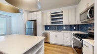 Located at 2125 E Apache Blvd in Tempe, Arizona, this thoughtfully designed 2-bedroom, 2-bathroom residence offers a clean, modern aesthetic throughout its single-floor layout. Light wood-style flooring flows seamlessly across every room, creating a warm and cohesive look.

The kitchen is a standout feature, showcasing crisp white cabinetry, white quartz countertops, and a striking deep-blue subway tile backsplash that extends to open display shelving. Stainless steel appliances — including a refrigerator, dishwasher, and range — complement the contemporary design, while a kitchen island with built-in shelving provides additional prep and storage space.

The bedrooms are bright and airy, each equipped with a ceiling fan and natural light from dual windows with white blinds. The spacious primary bedroom includes a dedicated walk-in closet with dual shelving systems. Both bathrooms are finished in a clean, minimalist style, featuring white cabinetry, light countertops, and a tub-shower combination.

The living room benefits from natural light and an exterior door, adding accessibility and openness to the space. Two closets offer ample storage throughout. The unit's clean white walls, consistent flooring, and modern fixtures create a bright, move-in-ready environment well suited to the Tempe lifestyle.