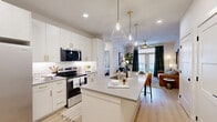 Located at 215 Reformation Pkwy in Canton, GA, this well-appointed two-bedroom, two-bathroom residence offers a thoughtfully designed single-level floor plan. The kitchen is a standout feature, showcasing white shaker cabinetry with gold hardware, stainless steel appliances, a subway tile backsplash, and a generous quartz-topped island with an undermount sink and seating for two, illuminated by clear glass pendant lights. Light wood-style flooring runs through the kitchen and main living areas.

The living room is bright and welcoming, with French doors opening to a balcony and a ceiling fan with a brushed gold finish. The primary bedroom offers comfortable carpeted flooring, a large window with natural light, and ample wall space, while both bedrooms include dedicated closets with wire shelving systems for organized storage.

The primary bathroom features light wood flooring, white cabinetry with gold hardware, a quartz countertop, an undermount sink with a matte black faucet, and a glass-enclosed shower. A neutral, warm color palette runs throughout the entire residence, creating a cohesive and modern aesthetic. The overall ambiance is clean, contemporary, and move-in ready.