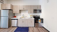 Located at 2930 Smallman Street in Pittsburgh's vibrant Strip District, this one-bedroom, one-bathroom unit offers a thoughtfully designed layout with an industrial-modern aesthetic. Exposed metallic ductwork runs throughout the space, adding an urban, loft-inspired character to the bright, white interior. Light wood-look flooring flows seamlessly across all rooms, enhancing the sense of continuity and warmth.

The open-concept kitchen is well-equipped with a full suite of stainless steel appliances, including a refrigerator, electric range with over-the-range microwave, and dishwasher. Light wood cabinetry pairs with a classic white subway tile backsplash and clean white countertops, creating a modern yet approachable aesthetic. The kitchen connects directly to the living area, which features elevated ceilings and a large window with access to a private balcony, bringing in natural light and outdoor views.

The bedroom is a comfortable, well-proportioned retreat with continued hardwood-style flooring. Two closets provide ample storage throughout the unit. The bathroom features a full tub-shower combination, a wide vanity with under-sink cabinetry, and a large mirror. An in-unit laundry area adds everyday convenience, completing this efficiently designed urban residence.