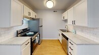 Located at 206 S Scientific St in High Point, NC, this single-story unit offers a practical and well-maintained layout across several distinct living spaces. The floor plan, as seen in the 3D overview, is thoughtfully arranged to separate living, dining, kitchen, and sleeping areas for functional everyday use.

The living area features warm wood-look laminate flooring, neutral gray walls, and a ceiling fan with integrated lighting, contributing to a comfortable and airy atmosphere. Natural light enters through a window fitted with blinds, adding brightness to the open space. Adjacent to the living area is a dedicated dining space, distinguished by a modern pendant light fixture and additional natural light from a nearby window.

The galley-style kitchen is well-equipped with white shaker cabinetry, black hardware, light stone-look countertops, a subway tile backsplash, and stainless steel appliances including a range, refrigerator, and dishwasher. Light wood-look flooring ties the kitchen together seamlessly.

The bedrooms are carpeted with neutral tones, each featuring a window with blinds and flush-mount ceiling lighting, creating calm and versatile spaces. The bathroom includes a full tub/shower combination, a vanity with storage, and wood-look flooring, maintaining a clean and functional aesthetic throughout.