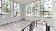 Located at 507 Grand St in Trenton, NJ, this two-story residence offers three bedrooms and two full bathrooms across a well-organized layout. The upper floor serves as the main living level and contains the bulk of the living space, featuring striking multi-pane windows with black frames that flood the rooms with natural light and offer pleasant views of surrounding greenery. Light-toned hardwood flooring runs throughout, lending a clean and cohesive aesthetic to the space.

The kitchen is equipped with white cabinetry, dark countertops, a stainless steel refrigerator, an electric range, and a drop-ceiling — all set over slate-toned tile flooring. A staircase with a black metal railing connects the two floors, with the upper landing area being particularly bright and open thanks to a large bank of multi-pane windows.

The bedrooms are bright and simply finished with white walls, hardwood floors, and grid-pane windows that bring in natural light. The primary bedroom offers a generous footprint with built-in closet shelving. Both bathrooms feature clean, all-white tub-shower combinations with built-in niche shelving. Hallways connect the rooms efficiently, completing a functional and light-filled floor plan throughout.
