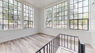 Located at 507 Grand St in Trenton, NJ, this two-story residence offers three bedrooms and two full bathrooms across a well-organized layout. The upper floor serves as the main living level and contains the bulk of the living space, featuring striking multi-pane windows with black frames that flood the rooms with natural light and offer pleasant views of surrounding greenery. Light-toned hardwood flooring runs throughout, lending a clean and cohesive aesthetic to the space.

The kitchen is equipped with white cabinetry, dark countertops, a stainless steel refrigerator, an electric range, and a drop-ceiling — all set over slate-toned tile flooring. A staircase with a black metal railing connects the two floors, with the upper landing area being particularly bright and open thanks to a large bank of multi-pane windows.

The bedrooms are bright and simply finished with white walls, hardwood floors, and grid-pane windows that bring in natural light. The primary bedroom offers a generous footprint with built-in closet shelving. Both bathrooms feature clean, all-white tub-shower combinations with built-in niche shelving. Hallways connect the rooms efficiently, completing a functional and light-filled floor plan throughout.