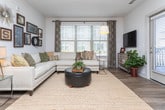 Located at 1921 Atkinson Rd in Lawrenceville, Georgia, this single-floor residence offers a thoughtfully designed layout with contemporary finishes throughout. The open-concept living area is bright and welcoming, featuring wood-style flooring, large windows that allow generous natural light, and direct access to an outdoor balcony. A curated gallery wall and tasteful décor accents add character to the living space, which flows seamlessly into a dedicated dining area.

The kitchen is outfitted with sleek, textured flat-front cabinetry in a warm gray tone, granite countertops, a classic subway tile backsplash, and a full suite of stainless steel appliances including a refrigerator, range, microwave, and dishwasher. Wood-style flooring continues throughout the kitchen, enhancing the cohesive aesthetic.

The primary bedroom is a comfortable retreat, featuring plush carpet, large windows with slatted blinds, and elegant decorative wall art. Additional bedrooms offer ample space with soft carpet flooring and convenient closet access.

The bathrooms are finished with granite-topped vanities, wood-style flooring, and clean white walls accented by framed artwork. One bathroom features a double-sink vanity with a full-width mirror, while another includes a tub-shower combination. Overall, the residence presents a polished, modern living environment suited for everyday comfort.