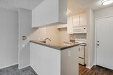 Located at 11902 Central Ave in Chino, California, this single-story unit offers a practical and comfortable layout designed for everyday living. The galley-style kitchen is efficiently arranged with white cabinetry providing ample storage above and below, granite-style countertops, a double stainless steel sink, and a white electric range with overhead microwave. A pass-through counter opens the kitchen to the living area, creating a connected, sociable flow between spaces. The living area features plush carpeting and sliding glass doors that lead to a private balcony, filling the room with natural light and offering outdoor views. Built-in shelving adds a functional design touch to the living space. The bedrooms are generously proportioned, each featuring soft carpeting, a textured ceiling, and windows with blinds that allow for natural light. A standout feature of the bedrooms is the full-wall mirrored sliding closet doors, which visually expand the rooms while providing substantial storage. The bathroom is well-appointed with a single-sink vanity featuring granite-style counters, white cabinetry, a shower/tub combo, and warm wood-look vinyl flooring. Throughout the unit, a consistent neutral color palette and textured ceilings contribute to a clean, cohesive aesthetic.