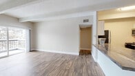 Located at 11100 E Dartmouth Ave in Denver, Colorado, this single-floor residence offers a thoughtfully updated interior with a cohesive blend of modern finishes and architectural character. Throughout the main living areas, durable wood-look flooring provides a warm, contemporary feel, while textured ceilings and exposed decorative beams add a distinctive charm.

The open living area is a standout feature, showcasing vaulted beam ceilings, a striking white-painted brick accent wall, and a sliding glass door that opens onto a private balcony overlooking mature, tree-lined surroundings. Natural light flows generously into the space, enhancing its airy atmosphere.

The kitchen is well-equipped with white shaker-style cabinetry, wood-toned countertops, a subway tile backsplash, and stainless steel appliances including a gas range, microwave, refrigerator, and dishwasher. A peninsula counter connects the kitchen to the main living and dining area, creating an efficient, open layout.

The bedroom features soft carpeting, exposed beam ceiling details, natural light from a large window, and the convenience of dual closets. The bathroom is clean and functional, with white tile surrounding a full soaking tub and shower combination, complemented by wood-look flooring. This residence delivers a comfortable, updated living environment in a serene Denver setting.
