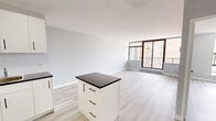 Located on the 11th floor at 810 Ouellette Avenue in downtown Windsor, Ontario, this one-bedroom, one-bathroom unit offers a bright and functional layout with a clean, modern aesthetic. Light wood-tone laminate flooring runs throughout, complementing the soft grey walls and white trim for a cohesive, contemporary feel.

The open-concept living and kitchen area forms the heart of the unit. The kitchen is well-appointed with white cabinetry, dark countertops, a subway tile backsplash, white appliances including a refrigerator and electric range, and a central island that provides additional prep and storage space. The living area is generously sized and bathed in natural light from large floor-to-ceiling windows and a sliding glass door that opens onto a private balcony, offering open views of the Windsor cityscape.

The bedroom is a comfortable, quiet retreat featuring a large window with city views, a baseboard heater, and a double sliding-door closet providing ample storage. The bathroom is finished with classic white tile surrounding a full soaker tub and shower combination, keeping the space clean and timeless.

This unit combines practical urban living with an elevated sense of light and openness, ideal for those seeking a well-located home in the heart of Windsor.