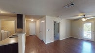 This single-story home features three bedrooms and two full bathrooms within a well-organized floor plan. The main living area is finished with rich, dark wood-look flooring that extends through the entryway, dining area, and into the kitchen. A ceiling fan with a light fixture is installed overhead, and a window along the exterior wall allows natural light to brighten the space. A dedicated dining area sits adjacent to the kitchen, providing a defined space for meals.

The kitchen is equipped with dark cabinetry, a double-basin stainless steel sink, laminate countertops, and a black refrigerator. A doorway from the kitchen leads to a laundry area. Textured ceilings are consistent throughout the main living spaces.

Each of the three bedrooms features plush carpet flooring and a ceiling fan. Two of the bedrooms include windows with blinds that admit natural light, while all three offer ample wall space for furniture placement.

Both bathrooms are finished with tile flooring and dark vanity cabinetry with light countertops. One bathroom includes a tub/shower combination with a curved curtain rod, while the other features a vanity with sink and toilet. The overall aesthetic is neutral and functional throughout.