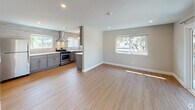 This single-floor residence presents a thoughtfully updated interior with a cohesive neutral palette and modern finishes throughout. The open-concept living and kitchen area serves as the heart of the home, featuring light hardwood-style flooring that enhances the sense of space and continuity. Natural light flows in through multiple windows, offering pleasant outdoor views of surrounding greenery.

The kitchen is a standout feature, showcasing grey shaker-style cabinetry paired with crisp white quartz countertops and a textured tile backsplash that extends to the ceiling. Stainless steel appliances include a gas range with a sleek wall-mounted hood, a dishwasher, and a refrigerator, all complemented by recessed and pendant lighting.

The bedrooms are carpeted in a warm neutral tone, each equipped with recessed lighting and windows that bring in natural light. One bedroom includes a dedicated closet and direct access to a utility area housing a stacked washer and dryer.

The bathrooms are finished with contemporary fixtures, including a full bath featuring large-format wall tiles, a soaking tub with a frameless sliding glass enclosure, and a vanity with a marble-style countertop and polished chrome hardware.