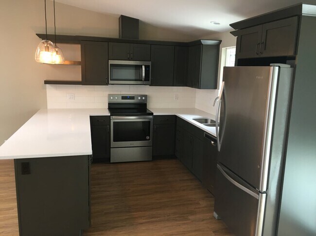New designed kitchen in open floor plan. beautiful quartz countertops, cabinets, stainless appliances, and wood laminate flooring - 1714 Madison Way