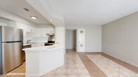 This single-floor residence offers a practical and thoughtfully designed layout encompassing one bedroom and two bathrooms. The kitchen is a standout feature, outfitted with crisp white shaker-style cabinetry, a classic white subway tile backsplash, light stone countertops, and a full suite of stainless steel appliances including a refrigerator, dishwasher, and electric range. A peninsula counter provides additional prep space and creates a natural transition into the open living area. Consistent large-format ceramic tile flooring flows throughout the main living spaces, lending a clean and cohesive aesthetic.

The bedroom is a comfortable size, featuring a ceiling fan with light fixture, two closets for ample storage, and a window that allows natural light and outdoor views of surrounding greenery. Two bathrooms serve the unit — one featuring wood-look tile flooring, white subway tile surround, and a shower-tub combination, while the other offers a vanity with white cabinetry, a backlit mirror, and light tile floors. Textured ceilings and recessed lighting are present throughout, adding to the functional character of the space. Neutral wall tones and an efficient floor plan make this a versatile and move-in-ready residence.