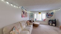 Located at 30 S Court St in Athens, Ohio, this two-floor unit offers a well-organized layout suited for comfortable everyday living. The main living area is carpeted and highlights a standout bay window with a built-in seat, providing a cozy nook filled with natural light. The open feel of the living room is complemented by a textured ceiling and ample space for seating arrangements.

The galley-style kitchen is efficiently designed, featuring wood-toned cabinetry, laminate countertops, a double basin sink, an electric range, a built-in dishwasher, and a microwave — all set on durable wood-look flooring. The layout maximizes functionality within a compact footprint.

The bedrooms are carpeted and vary in size, with several featuring vaulted or angled ceilings that add architectural character. Each room includes windows that bring in natural light, and some feature sliding or hinged closets for storage. The second floor, accessible via a staircase with white balusters, houses additional bedroom space.

The bathroom includes a single-sink vanity with wood-trimmed cabinetry, a toilet, and a shower-tub combination. Neutral wall tones throughout the unit create a clean, cohesive aesthetic that adapts easily to a variety of interior styles.