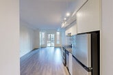 This 340 square foot apartment in downtown Toronto offers a smart, efficient living space. The open-concept design features a living room that seamlessly integrates with the kitchen area, maximizing the available space. Large windows flood the room with natural light and provide urban views, enhancing the sense of spaciousness.

The kitchen is equipped with modern stainless steel appliances, including a full-sized refrigerator, oven, and dishwasher. White cabinetry and a neutral backsplash contribute to the clean, contemporary aesthetic. The living area's hardwood flooring extends throughout, unifying the space and adding warmth.

The bathroom, while compact, is well-appointed with a full-sized bathtub, modern fixtures, and neutral tiling. A hallway provides access to all areas of the apartment and likely includes storage solutions.

The apartment's layout is carefully considered to make the most of every square foot, ideal for single occupants or couples seeking a minimalist urban lifestyle. Located at 22 Wellesley St W, this property offers the convenience of city living in a thoughtfully designed, modern space.