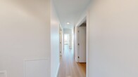This contemporary multi-bedroom unit in Calgary, AB offers a well-designed layout across a single floor, combining modern finishes with practical functionality. Light-toned hardwood flooring flows throughout, creating a warm and cohesive aesthetic from room to room.

The open-concept kitchen is a standout feature, showcasing natural wood cabinetry, a dark-topped island with pendant lighting, white tile backsplash, and stainless steel appliances including a full-size refrigerator. The kitchen connects seamlessly to the living area, where expansive floor-to-ceiling windows flood the space with natural light and frame impressive views of the Calgary skyline and surrounding cityscape.

A bright hallway connects the three bedrooms, each featuring clean white walls and large windows that capture abundant sunlight and outdoor views of the city and green canopy below. The bedrooms include sliding closet doors for efficient storage.

The two bathrooms are finished with large-format stone-look floor tiles, light wood vanities, dark countertops, and modern fixtures. The primary bathroom is particularly spacious, featuring a wide double-sink vanity and generous windows overlooking the city.

The overall ambiance is clean, bright, and contemporary, with a neutral palette that highlights the quality of materials and the exceptional elevated views throughout.