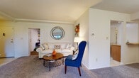 Located at 2 Garston Court in Cockeysville, Maryland, this single-floor residence offers a thoughtfully arranged layout designed for comfortable everyday living. The living room serves as the heart of the home, featuring plush carpeting, vaulted ceiling details, and a bright, neutral color palette that creates an open and airy atmosphere. The space connects naturally to adjacent areas, providing a cohesive flow throughout the home. The kitchen is efficiently designed with warm wood cabinetry, ample counter space, and white appliances including a gas range and refrigerator, all set atop easy-care flooring. A dedicated dining area features an elegant chandelier overhead, adding a touch of sophistication to mealtimes. The bedroom is generously proportioned, offering soft carpeting, large windows dressed with sheer curtains that allow natural light to filter in, and direct access to a walk-in closet. Two bathrooms serve the home, each finished with classic white vanities, mirrored medicine cabinets, and tile flooring. The overall ambiance throughout the residence is calm and neutral, offering a clean, move-in-ready canvas suited to a variety of personal styles.