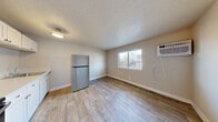 Located at 230 N 11th St in Las Vegas, NV, this studio unit offers a practical and efficiently designed single-floor layout. The main living area is open and airy, featuring wood-look plank flooring, neutral-toned walls, and a textured ceiling. A wall-mounted air conditioning unit and a window with blinds provide both climate control and natural light, enhancing the sense of space in the room. The kitchen is thoughtfully equipped with white shaker-style cabinetry, a stainless steel refrigerator, an electric range, and a countertop sink — all finished with the same durable wood-look flooring that runs throughout the unit. Flush-mount lighting keeps the kitchen well lit. A hallway connects the living and kitchen spaces to the rest of the unit, leading to a dedicated closet for storage and a full bathroom. The bathroom features a clean, white-tiled shower and tub combination, a toilet, a single vanity with sink, and a wall-mounted towel ring, all presented in a crisp, neutral palette. The consistent flooring, white trim, and understated finishes throughout give the unit a cohesive, move-in-ready feel well suited for urban living in downtown Las Vegas.