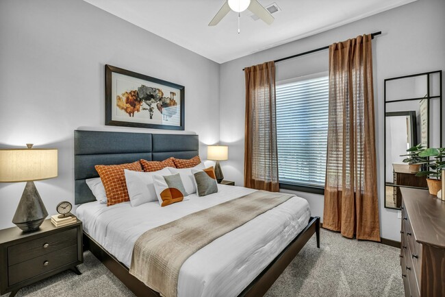 Primary bedroom with carpet and a ceiling fan - The Brick and Mortar District Apartments