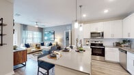 Located in Saint Johns, FL, this 2-bedroom, 2-bathroom residence offers a thoughtfully designed single-story layout that combines comfort and modern style. The open-concept living area is anchored by a spacious living room with wood-look plank flooring, a ceiling fan, and large windows dressed with sheer curtains and plantation shutters that invite abundant natural light. A glass door provides access to the outdoors, enhancing the airy feel of the space.

The kitchen is a standout feature, showcasing crisp white shaker-style cabinetry, a white subway tile backsplash, sleek quartz countertops, and a full suite of stainless steel appliances including a range, microwave, dishwasher, and refrigerator. Elegant pendant lights illuminate a generously sized island with bar seating, making it ideal for casual dining and entertaining.

Both bedrooms are well-proportioned, featuring wood-look flooring, ceiling fans, and ample closet space, including a walk-in closet with wire shelving in the primary bedroom. The bathrooms are finished with white cabinetry, quartz-topped vanities, large framed mirrors, and wood-look tile flooring, with the primary bath including a glass-enclosed shower. The overall palette of soft neutrals and cool blues creates a cohesive, contemporary ambiance throughout.