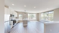 Located at 185 W Kelly St in Metuchen, NJ, this well-appointed 2-bedroom, 2-bathroom residence offers a thoughtfully designed, single-floor layout with a clean, contemporary aesthetic. The open-concept kitchen and living area serves as the heart of the home, featuring white shaker cabinetry, crisp white countertops, a center island with a built-in sink, stainless steel appliances, and pendant lighting. Large windows flood the space with abundant natural light and offer pleasant outdoor views of the surrounding neighborhood. Light-toned, hardwood-style flooring runs consistently throughout, enhancing the sense of openness and flow. The living area extends generously from the kitchen, complemented by an additional half-wall that adds architectural definition to the space. Both bedrooms are comfortably sized, each featuring windows with natural light and outdoor views, along with neutral warm-toned walls that create a calm, restful atmosphere. The two bathrooms are finished in a cohesive modern style, with white vanities, light countertops, and coordinating fixtures. One bathroom features a shower-tub combination, while the other offers a clean, functional layout. Recessed lighting and consistent neutral tones throughout the residence contribute to a bright, cohesive, and move-in-ready living environment.