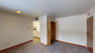 Located at 224 Highland Ave in East Lansing, Michigan, this single-floor unit offers a straightforward and functional layout well-suited for everyday living. The open living area is finished with plush wall-to-wall carpeting and clean white walls, creating a neutral and adaptable space. A wooden bi-fold closet door adds a warm, classic touch, while a ceiling vent ensures consistent climate control throughout. The compact kitchen is efficiently arranged with white cabinetry, a sink, and a range, all set over easy-to-clean hard flooring and illuminated by overhead lighting. Adjacent to the main living area, the bedroom features large windows dressed with vertical blinds, allowing ample natural light to filter in while offering views of the surrounding neighborhood. The bedroom's carpeted floor and warm-toned wood baseboards echo the cohesive design found throughout the unit. The full bathroom is a notable feature, showcasing retro orange and pink square wall tiles that lend a distinctive vintage character to the space. It includes a shower-tub combination, toilet, and single vanity with a wall-mounted mirror, along with a window that brings in natural light. Overall, this unit presents a clean, no-frills living environment in a convenient East Lansing location.
