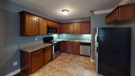 Located at 360 N 1st in El Cajon, Unit #43 is a well-appointed single-story residence designed for comfortable everyday living. The kitchen serves as a functional centerpiece, featuring rich wood cabinetry, granite-style countertops, and a full suite of stainless steel appliances including a range, dishwasher, microwave, and refrigerator. Warm tile flooring anchors the kitchen space, which flows seamlessly into the open living and dining area finished with wood-style flooring and clean crown molding details. The unit includes multiple bedrooms, each carpeted for comfort and fitted with windows dressed in horizontal or vertical blinds that allow for natural light. One bedroom benefits from a walk-in closet, while another offers an exterior view. Two full bathrooms serve the unit — one featuring a granite-topped vanity and a tub/shower combination with sliding glass doors, and a second with a dark-stained vanity and a curved-rod shower enclosure over a standard tub. Neutral tones throughout create a cohesive and move-in-ready atmosphere. The overall layout, as seen in the dollhouse view, is efficiently organized with clear separation between living and sleeping areas.