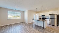 Located at 2515 Orchard Circle Dr in Traverse City, Michigan, this well-designed one-bedroom, one-bathroom unit offers a clean, modern aesthetic throughout its efficiently laid-out single floor. Light hardwood-style flooring flows seamlessly across all living spaces, creating a cohesive and bright atmosphere.

The open-concept kitchen and living area serves as the heart of the unit. The kitchen is outfitted with white shaker-style cabinetry, stainless steel appliances including a refrigerator, range, and microwave, and a central island with a dark countertop and built-in sink. A trio of pendant lights hang above the island, adding stylish task lighting. A glass-panel door leads directly to a private balcony, filling the kitchen with natural light and outdoor views.

The living area is bright and open, anchored by a large window with exterior views of the surrounding neighborhood. The bedroom offers a comfortable footprint with its own generously sized window, allowing ample natural light. A dedicated closet provides convenient storage.

The bathroom features a white vanity with under-cabinet storage, a well-lit mirror, a window for natural light, and a shower/tub combination. A hallway connects all rooms efficiently. A stacked washer and dryer is also included within the unit, adding everyday convenience to this thoughtfully designed Traverse City residence.