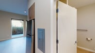 Located at 1280 SE Nehalem St in Portland, Oregon, this modern single-floor unit offers a thoughtfully designed layout with clean, contemporary finishes throughout. Light-toned luxury vinyl plank flooring flows seamlessly through the main living areas, complementing the neutral warm-beige walls and creating a bright, cohesive aesthetic.

The kitchen is well-appointed with wood-toned cabinetry extending to the upper walls, providing generous storage space. Stainless steel appliances include a gas range, built-in microwave, dishwasher, and refrigerator, while white countertops and a tile backsplash add a polished, modern touch. Recessed and linear lighting illuminates the space efficiently.

The open living area benefits from abundant natural light, with large sliding glass doors leading directly to a private outdoor deck. Greenery from the surrounding landscape is visible through the glazing, creating a pleasant indoor-outdoor connection.

The bathroom features a wood-grain vanity with a quartz-style countertop, a large wall mirror, and a shower-tub combination, maintaining the same cohesive design language found throughout the unit. Additional practical details include an electrical panel, recessed entryway hooks, and thoughtfully placed outlets and vents. The unit's modern construction and clean finishes make it a functional and attractive space in Portland's SE neighborhood.