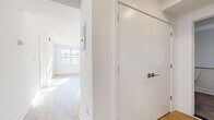 This newly constructed single-floor unit offers a clean, modern aesthetic throughout, defined by crisp white walls, light hardwood-style flooring, and an abundance of natural light. The open-concept layout creates a seamless flow between living areas, with recessed lighting complementing the sunlight that pours in through multiple large windows overlooking the surrounding streetscape.

The kitchen is well-appointed with white shaker-style cabinetry, light quartz countertops, a stainless steel undermount sink with a contemporary gooseneck faucet, and a full suite of stainless steel appliances including a refrigerator, range, microwave, and dishwasher. The galley-style configuration maximizes efficiency while maintaining a sleek, uncluttered appearance.

The living and sleeping areas are generously proportioned, with large windows fitted with blinds that bring in ample daylight while offering privacy. Closet space is provided via full-height flush-panel doors with brushed nickel hardware, maintaining the unit's streamlined design language.

The bathroom is designed to ADA accessibility standards, featuring a wall-mounted sink, grab bars, large-format tile flooring in a neutral tone, and a backlit vanity mirror, combining practicality with a polished finish throughout.