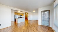 Located at 4040 26th Ave SW in Seattle, WA, this well-appointed 2-bedroom, 2-bathroom apartment offers a thoughtfully designed single-floor layout. The open-concept living, dining, and kitchen area serves as the heart of the unit, featuring warm hardwood-style flooring, clean white walls, and floor-to-ceiling windows that flood the space with natural light and frame views of the surrounding neighborhood. The kitchen is equipped with stainless steel appliances—including a refrigerator, range, microwave, and dishwasher—alongside light wood cabinetry and a functional island with a built-in sink. A sliding glass door leads to a private balcony, extending the living space outdoors. A well-lit hallway connects the main living area to the two bedrooms, both of which feature plush carpeting and large windows with outdoor views. The primary bedroom is generously proportioned and benefits from ample closet space—five closets are distributed throughout the unit. The two bathrooms include one with a tub/shower combination and one with a standalone glass-enclosed shower, both with hardwood-style flooring. A dedicated entrance and hallway complete this clean, modern home.