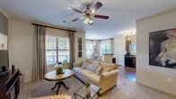 Located at 601 Giddings Ct in Augusta, GA, this thoughtfully designed 2-bedroom, 2-bathroom residence offers a comfortable and functional single-floor layout. The open-concept living room greets you with plush carpeting, crown molding, a ceiling fan, and multiple windows dressed with elegant drapes and blinds that invite abundant natural light. A built-in electric fireplace anchors the room, adding warmth and character. The adjacent dining area is framed by a bay of windows, creating a bright, airy nook ideal for entertaining. The kitchen features rich dark cabinetry, dark countertops, a double sink, and black appliances including a range, microwave, and refrigerator, all complemented by hardwood-style flooring. The generously sized primary bedroom includes a ceiling fan, walk-in closet, and plush carpeting, while the second bedroom mirrors the same comfort with natural light and ample storage. Both bathrooms are finished with dark countertops and wood-toned cabinetry. A dedicated in-unit laundry room with side-by-side washer and dryer adds everyday convenience. Two hallways and two closets round out the well-organized floor plan, making this residence as practical as it is inviting.