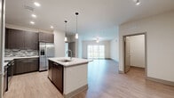 Located at Lakewood Ranch Boulevard in Sarasota, FL, this well-appointed 2-bedroom, 2-bathroom single-story residence offers a thoughtfully designed open-concept layout. The combined kitchen and living area serves as the heart of the home, anchored by a central kitchen island with a white quartz countertop, undermount sink, and elegant pendant lighting. Dark espresso cabinetry, a tile mosaic backsplash, stainless steel appliances — including a French door refrigerator and built-in microwave — complete the kitchen. Light wood-style flooring runs throughout the main living areas, complementing the neutral color palette and creating a bright, cohesive feel. The spacious living room features a ceiling fan and sliding glass door that fills the space with natural light. Both bedrooms are finished with plush carpeting and include dedicated closets; the primary bedroom features a generously sized walk-in closet with built-in wire shelving. The bathrooms are finished with light tile flooring, wood-toned vanities, white quartz counters, and backlit mirrors. A dedicated laundry room houses a full-size washer and dryer. The clean, modern aesthetic throughout makes this residence a comfortable and functional Sarasota home.
