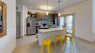 This well-designed single-floor residence offers a seamless blend of modern aesthetics and functional living. The open-concept layout connects the kitchen, dining, and living areas into one cohesive, light-filled space. The kitchen is a standout feature, outfitted with rich dark wood cabinetry, stainless steel appliances including a refrigerator, range, and microwave, and a granite-topped island with bar seating — ideal for both casual meals and entertaining. Light-toned flooring runs throughout, lending a clean and airy feel to the space.

The living area flows naturally from the kitchen, providing a comfortable and versatile gathering space. The bedroom is a serene retreat, anchored by a bold dark accent wall that creates a dramatic contrast against crisp white bedding and warm, layered textiles. Light wood flooring continues here, complemented by a wall-mounted television and direct sightlines to the bathroom.

The bathroom is finished with a granite-topped vanity featuring warm wood cabinetry, a tub and shower combination with a bold patterned curtain, and neutral tile flooring. Clean white walls and thoughtfully chosen décor give the space a polished, contemporary feel. Overall, this residence offers a cohesive and stylish living environment with modern finishes and a well-considered design throughout.