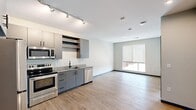 Located at 281 Willow St in Fort Collins, Colorado, this thoughtfully designed one-bedroom, one-bathroom unit offers a modern and efficient single-floor layout. Light hardwood flooring flows throughout the entire space, complemented by neutral gray walls and bold blue baseboards that add a contemporary accent.

The open-concept kitchen and living area serves as the heart of the unit. The kitchen is well-appointed with gray flat-front cabinetry, open shelving, granite countertops, and a full suite of stainless steel appliances including a refrigerator, electric range, microwave, and dishwasher. A track lighting system overhead ensures excellent task illumination. The kitchen opens seamlessly into the living area, which benefits from natural light through a large window fitted with a roller shade.

The bedroom is a comfortable, well-proportioned room featuring a window with views of the surrounding Fort Collins streetscape, allowing ample natural light to fill the space. Two closets provide practical storage solutions. The bathroom features a walk-in glass-enclosed shower with clean white surround panels and modern matte black fixtures. The unit also includes a distinctive blue entry door, adding a stylish focal point to the overall interior design.
