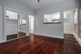 Located at 2810 Leeward Ave in Los Angeles, CA 90005, this single-floor space blends classic architectural character with modern updates. The living area is a standout, showcasing a full exposed brick accent wall that adds warmth and texture, complemented by rich, deep-toned hardwood floors that run throughout the unit. A ceiling fan with an integrated light fixture anchors the room, while white-trimmed windows allow natural light to filter in, brightening the space. A wall-mounted heater provides functional comfort.

The kitchen is thoughtfully designed with crisp white shaker-style cabinetry, dark countertops, a stainless steel sink, and a gas range, conveying a clean and efficient workspace. A pass-through cutout connects the kitchen to the main living area, enhancing the open feel of the layout.

The bedroom features the same warm hardwood flooring, a ceiling fan, and a mirrored sliding closet door that reflects light and adds a sense of spaciousness. Neutral gray walls create a calm, versatile backdrop throughout. The bathroom includes classic white subway tile, contributing to the unit's timeless aesthetic. The overall ambiance is one of character-rich, urban living with thoughtful, functional updates.