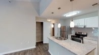 Located at 1500 Sunbow Falls Ln in Raleigh, North Carolina, this single-floor residence offers a well-designed layout with contemporary finishes throughout. The kitchen serves as a central highlight of the home, featuring granite-look countertops, a stainless steel sink set into a peninsula-style island, and stainless steel appliances including a refrigerator and electric range. White cabinetry with clean lines provides ample storage, while subway tile backsplash adds a modern touch. Pendant lighting hangs above the island, complementing the flush-mount and recessed lighting that keeps the space well-lit. The flooring throughout features rich, dark hardwood-style planks that contrast elegantly with the light-toned walls and trim. The open layout connects the kitchen to the adjacent living areas, creating a cohesive and airy feel. A spacious walk-in closet with built-in shelving is conveniently accessible from the main living area, offering excellent organizational storage. Textured ceilings and angled architectural details add dimension to the interior. The overall ambiance is clean, modern, and move-in ready, reflecting a thoughtful approach to practical residential design in a desirable Raleigh location.
