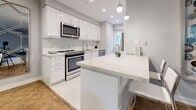 Located on Bayview Mews Lane in Toronto, this thoughtfully designed one-bedroom, one-bathroom home offers a smart and functional layout across a comfortable single floor, with wooden staircase access adding a warm architectural touch. The renovated kitchen is a standout feature, boasting crisp white cabinetry, a veined quartz waterfall island with bar seating, stainless steel appliances, subway tile backsplash, and large-format porcelain tile flooring — all illuminated by recessed and pendant lighting. The dining room is bright and inviting, with windows framing lush greenery, warm parquet hardwood flooring, and an elegant large-panel mirror that amplifies the sense of space. The living room features natural light through a sizable window with tree views, parquet floors, and a wall-mounted mini-split unit for year-round comfort. The spacious bedroom offers generous proportions, parquet hardwood flooring, and a wide window with peaceful outdoor views. The bathroom is clean and modern with a soaker tub and white tile surround. Additional highlights include three closets for ample storage, a private balcony, and in-unit laundry — completing a practical and polished living space.