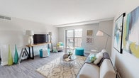 This single-floor residence at Park Plaza offers a thoughtfully designed open-concept layout finished with durable wood-style flooring throughout. The living area is generously proportioned, featuring neutral grey walls and a large sliding glass door that opens onto a private balcony, allowing natural light to fill the space and providing views of the surrounding cityscape. The living room flows seamlessly into a secondary seating or flex area, offering versatile functionality.

The kitchen is well-equipped with white shaker-style cabinetry, a double stainless steel sink, light laminate countertops, and a full suite of stainless steel appliances, including a range, over-the-range microwave, and refrigerator. Recessed lighting and a practical galley-style configuration make the kitchen both functional and bright.

The unit includes two bedrooms, each featuring wood-style flooring, neutral painted walls, and windows that frame outdoor views. Both rooms offer a calm, restful atmosphere with ample space for furnishings.

The full bathroom includes a tub-shower combination, a white vanity with stone-style countertop, and wood-style flooring, maintaining the cohesive modern aesthetic found throughout the unit. The overall ambiance is clean, contemporary, and move-in ready.
