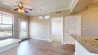This well-designed one-bedroom, one-bathroom unit makes efficient use of its single-floor layout, offering a cohesive and functional living environment with consistent finishes throughout. The living room serves as the central gathering space, featuring wood-look plank flooring, crown molding, a ceiling fan with light fixture, and a window alongside a glass-paneled exterior door that fills the room with natural light. Transom windows positioned above interior doorways add an architectural detail while allowing additional light to flow between spaces.

The kitchen is appointed with dark espresso cabinetry, granite-style countertops, a subway tile backsplash, stainless steel appliances including a refrigerator and range, and a breakfast bar with a built-in sink — providing practical prep and casual dining space. Wood-look flooring continues through the kitchen, maintaining visual continuity.

The bedroom offers plush carpet, a ceiling fan, and a generously sized window with outdoor views, creating a comfortable and restful environment. A dedicated closet provides organized storage. The bathroom features wood-look flooring, a full soaking tub with white tile surround, a granite-topped vanity, and a large mirror, completing this functional and neatly finished unit.