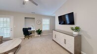 This well-appointed single-story residence in Greenwood, South Carolina offers a thoughtfully designed layout across two bedrooms and two bathrooms. Neutral warm-gray tones throughout create a cohesive, calming ambiance that ties each room together seamlessly.

The galley-style kitchen features white shaker cabinetry, granite countertops, stainless steel appliances, and tile flooring, with direct sightlines into the adjacent dining area. The dining space is distinguished by wainscoting along the lower walls, a brushed nickel chandelier, and decorative wall accents, lending a polished, refined character to everyday meals.

The living room offers plush carpeting and natural light from a sliding glass door, creating a comfortable gathering space. Both bedrooms are carpeted and include ceiling fans with light fixtures. The primary bedroom provides a dedicated walk-in closet with wire shelving and natural light from a window. The primary bathroom features large-format tile flooring, a granite vanity, and a glass-enclosed shower.

A dedicated laundry room houses a full-size washer and dryer. A connecting hallway ties all areas together efficiently, maximizing the functionality of this compact yet complete home.