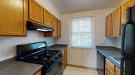 Located at 62 Crestview Ln in Fitchburg, Massachusetts, this single-floor unit offers a practical and well-organized layout across its living spaces. The kitchen is equipped with warm oak cabinetry, dark countertops, a black gas range with overhead ventilation, and a dishwasher. Light-colored tile flooring and a window overlooking greenery give the kitchen a bright, functional feel. The full bathroom features white tile walls, a tub-shower combination, a single-sink vanity with white cabinetry, a wall mirror, and tile flooring — all illuminated by a natural light-admitting window. The living area showcases warm hardwood-style flooring, white walls, and a closet, with windows that invite ample natural light and views of the surrounding neighborhood. A wall-mounted HVAC unit provides climate control. The bedrooms are finished with neutral carpeting, generous closet space, and windows that keep each room bright and airy. One bedroom features a paneled door and connects seamlessly to the hardwood-floored living area. Throughout the unit, the clean, neutral palette and consistent finishes create a cohesive and welcoming atmosphere well-suited for comfortable everyday living.