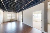 Located at 617 Hiawatha Blvd E in Syracuse, NY, this 2-bedroom, 1-bathroom unit offers a distinctive industrial aesthetic blended with functional living spaces. The spacious living room immediately captures attention with its dramatic exposed ceiling structure — dark-painted joists and beams that lend a loft-like character — along with gleaming hardwood floors that reflect natural light streaming through multiple windows. Exposed structural columns punctuate the open area, reinforcing the industrial charm.

The kitchen is well-equipped with warm wood cabinetry, stainless steel appliances including a refrigerator, range, and built-in microwave, complemented by light tile flooring and a window that brings in natural light. The two bedrooms offer a comfortable scale; the primary bedroom features hardwood flooring, a large arched window set against a white brick wall, and an exposed ceiling that continues the unit's industrial theme, while the second bedroom is carpeted and benefits from generous natural light through multiple windows with outdoor views.

The full bathroom is finished with yellow tile flooring, a tub/shower combo, a wood-toned vanity with a stone-top, and clean white walls. Three closets throughout the unit provide ample storage. Baseboard heating is present throughout, ensuring year-round comfort in this characterful Syracuse residence.