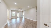 This single-story home offers a thoughtfully designed layout encompassing three bedrooms, two bathrooms, an open-concept kitchen and living area, a hallway, and a welcoming entrance. Light-toned hardwood-style flooring runs consistently throughout, creating a cohesive and clean aesthetic across the entire home.

The combined kitchen and living room forms the heart of the space. The kitchen is well-equipped with white shaker-style cabinetry, granite countertops, stainless steel appliances including a dishwasher and refrigerator, and a classic white subway tile backsplash. A central island provides additional counter space and casual seating. The adjacent living area is bright and open, featuring recessed lighting, a ceiling fan, and windows that invite natural light from outside.

The spacious primary bedroom includes its own en-suite bathroom, which features a soaking tub with tile surround and two separate doors leading to additional closet or utility spaces. The two additional bedrooms are comfortably sized, each with windows offering views of the surrounding greenery and fitted with ceiling fans for added comfort.

The secondary bathroom includes a full tub-shower combo with white tile surround and brushed nickel fixtures. Neutral warm-beige walls and bright white trim are consistent throughout, giving the home a clean, modern, and move-in-ready appearance.