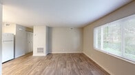 Located at 8460 Hospital Dr in Douglasville, GA, this single-floor, one-bedroom, one-bathroom unit offers a practical and comfortable layout ideal for individuals or couples. The open kitchen and living area is designed for everyday functionality, featuring white cabinetry that extends to the ceiling, light-toned countertops, a full-size electric range, and a refrigerator. Durable wood-look flooring runs throughout the kitchen and living areas, adding warmth and a clean, modern aesthetic. The living room is bright and welcoming, with large windows that allow natural light to pour in and offer pleasant outdoor views of the surrounding greenery. A ceiling fan with a light fixture enhances comfort in the well-proportioned bedroom, which is finished with soft carpeting underfoot. The bedroom also features dual sets of bifold closet doors, providing ample storage space. The bathroom is clean and straightforward, with a full tub-shower combination finished in classic white tile, a toilet, and a small privacy window that allows natural ventilation. Throughout the unit, neutral wall tones and consistent finishes create a cohesive and inviting atmosphere.