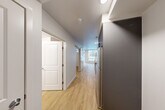 Located at 5 W Roy St in Seattle's desirable Queen Anne neighborhood, this one-bedroom, one-bathroom unit offers a thoughtfully designed layout that maximizes every square foot. Light-toned hardwood-style flooring runs throughout, creating a cohesive and clean aesthetic from room to room.

The combined kitchen and living area serves as the heart of the unit. The galley-style kitchen is outfitted with grey cabinetry, white quartz countertops, a textured tile backsplash, and a full suite of stainless steel appliances, including an electric range, microwave, and refrigerator. A large window at the end of the living area floods the space with natural light, while a sliding glass door provides direct access to a private balcony.

The bedroom offers a comfortable, private retreat, complemented by two dedicated closets for ample storage. A sliding barn-style door adds a modern design touch to the space.

The bathroom and laundry room are conveniently combined, featuring a full soaking tub with a curved shower rod, matte black fixtures, a grey vanity, and wood-look flooring that ties back to the rest of the unit.

A central hallway connects all areas efficiently, lined with recessed and flush-mount lighting for a bright, welcoming atmosphere throughout.