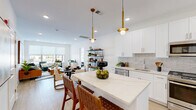 This thoughtfully designed one-bedroom, one-bathroom residence in Bound Brook, NJ offers a well-appointed single-floor layout that maximizes both comfort and functionality. The open-concept living area is anchored by light hardwood flooring throughout, crisp white walls, and recessed lighting that creates a bright, airy atmosphere.

The kitchen is a standout feature, showcasing white shaker cabinetry, a striking marble-veined quartz waterfall island with bar seating, a subway tile backsplash, stainless steel appliances, and elegant gold pendant lighting. The space flows seamlessly into the dining and living areas, where large windows invite abundant natural light.

The generously sized primary bedroom provides a tranquil retreat with recessed lighting, ample room, and direct access to the full bathroom. The bathroom features a floating white vanity with quartz countertops, a large mirror, and refined tile flooring.

A dedicated office space offers a quiet area for focused work and conveniently houses an in-unit stacked washer and dryer. A closet provides additional storage. The cohesive modern design throughout — from the gold-accented fixtures to the neutral palette — gives this residence a polished, contemporary character.