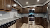 Located at 890 Tallmadge Rd in Kent, Ohio, this single-floor residence offers a well-designed layout with modern finishes throughout. The kitchen is a standout feature, showcasing rich dark wood cabinetry, granite countertops, a subway tile backsplash, and a full suite of stainless steel appliances including a range, over-the-range microwave, dishwasher, and refrigerator. Light wood-tone luxury vinyl plank flooring runs through the kitchen and main living areas, lending a warm, cohesive feel to the space. The open living and dining area is generously sized, with neutral gray walls, recessed lighting, and ceiling fans that enhance both comfort and functionality. Large windows dressed with horizontal blinds allow natural light to filter into the bedrooms, each of which features plush wall-to-wall carpeting and ample closet space. The primary bedroom includes a walk-in closet and direct access to an en-suite bathroom. Both bathrooms are finished with dark wood vanities, granite countertops, undermount sinks, and wood-look vinyl flooring, maintaining a consistent and polished aesthetic throughout the home.