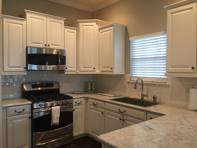 kitchen with marble counter, farmhouse steel sink, stainless steel gas stove, cabinets with underneath lighting - 15403 Barossa Valley St