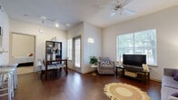 This single-story, 2-bedroom, 2-bathroom home offers a practical and comfortable layout designed to maximize every square foot. The open-concept living, dining, and kitchen area forms the heart of the home, featuring rich hardwood-style flooring throughout. The living room is bright and inviting, with large windows that bring in ample natural light, a ceiling fan overhead, and a textured ceiling. A glass door provides additional light and outdoor access. The dining area sits adjacent to the living space, complemented by a track-lit ceiling and an open shelving unit.

The kitchen is efficiently designed with white cabinetry, light countertops, and black appliances including a range and built-in microwave, all set atop matching hardwood-style floors.

Both bedrooms are carpeted and offer a cozy, quiet retreat. The primary bedroom is a generous size, featuring a window with outdoor views, while the second bedroom is similarly comfortable with its own window and closet. Each room benefits from soft, natural light filtered through blinds and curtain panels.

The two bathrooms mirror each other in style, each featuring a tub-shower combination, white cabinetry with light countertops, and hardwood-style flooring — providing clean, functional spaces throughout.